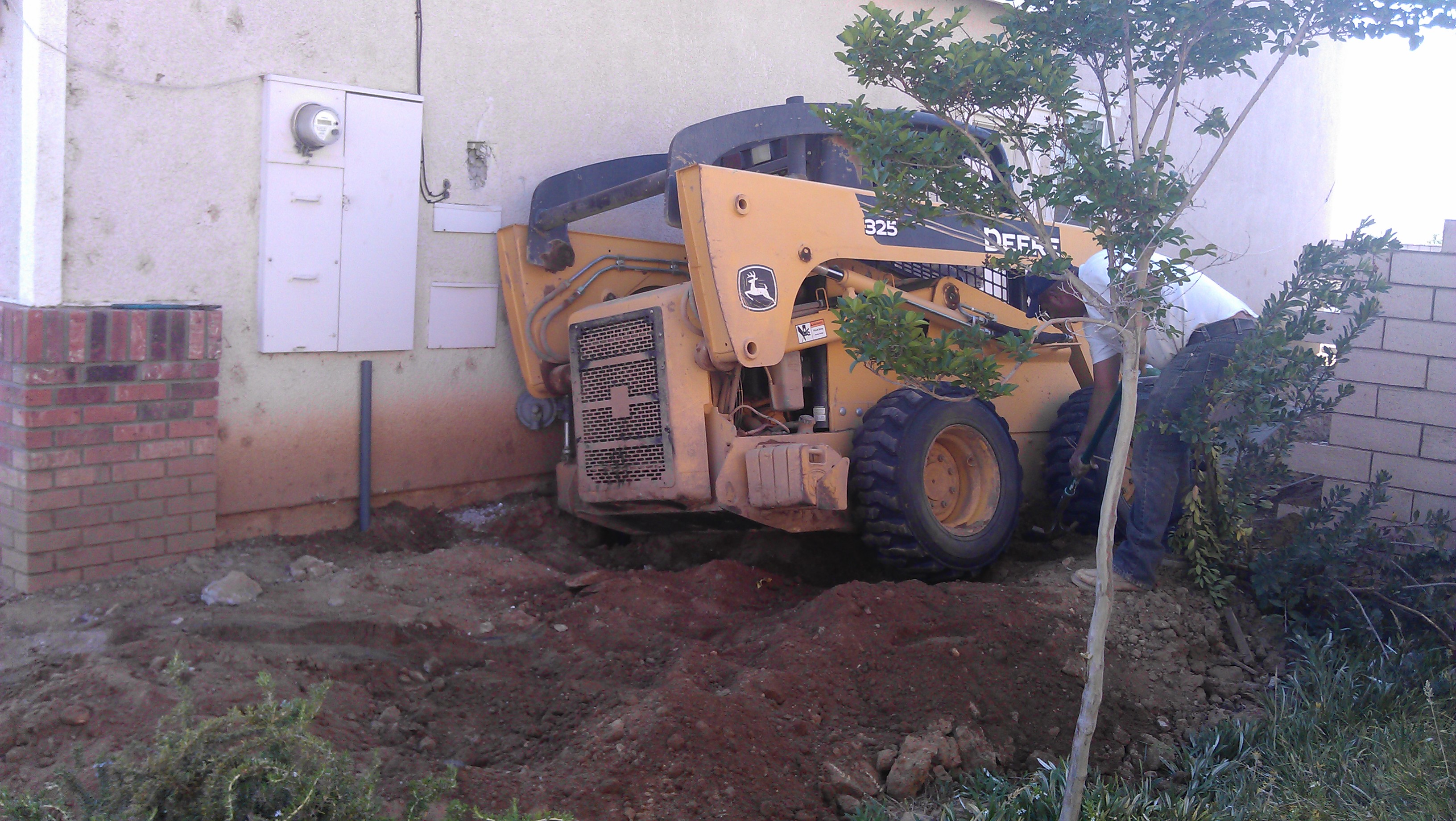 Humberto Garcia of Oasis Custom Pools runs the tractor into my house.breaking open the stucco