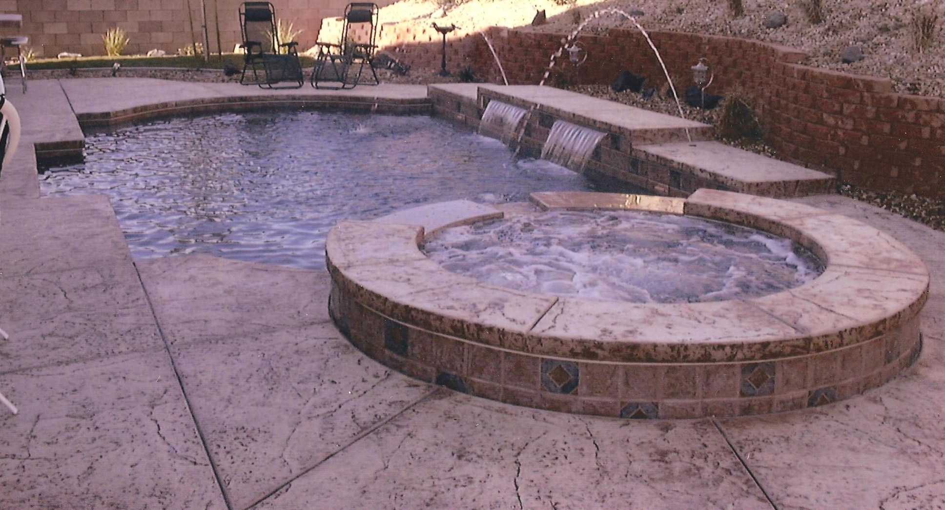 POOL WITH 12" RAISED SPA, DECK JETS SURROUNDED WITH STAMPED CONCRETE
