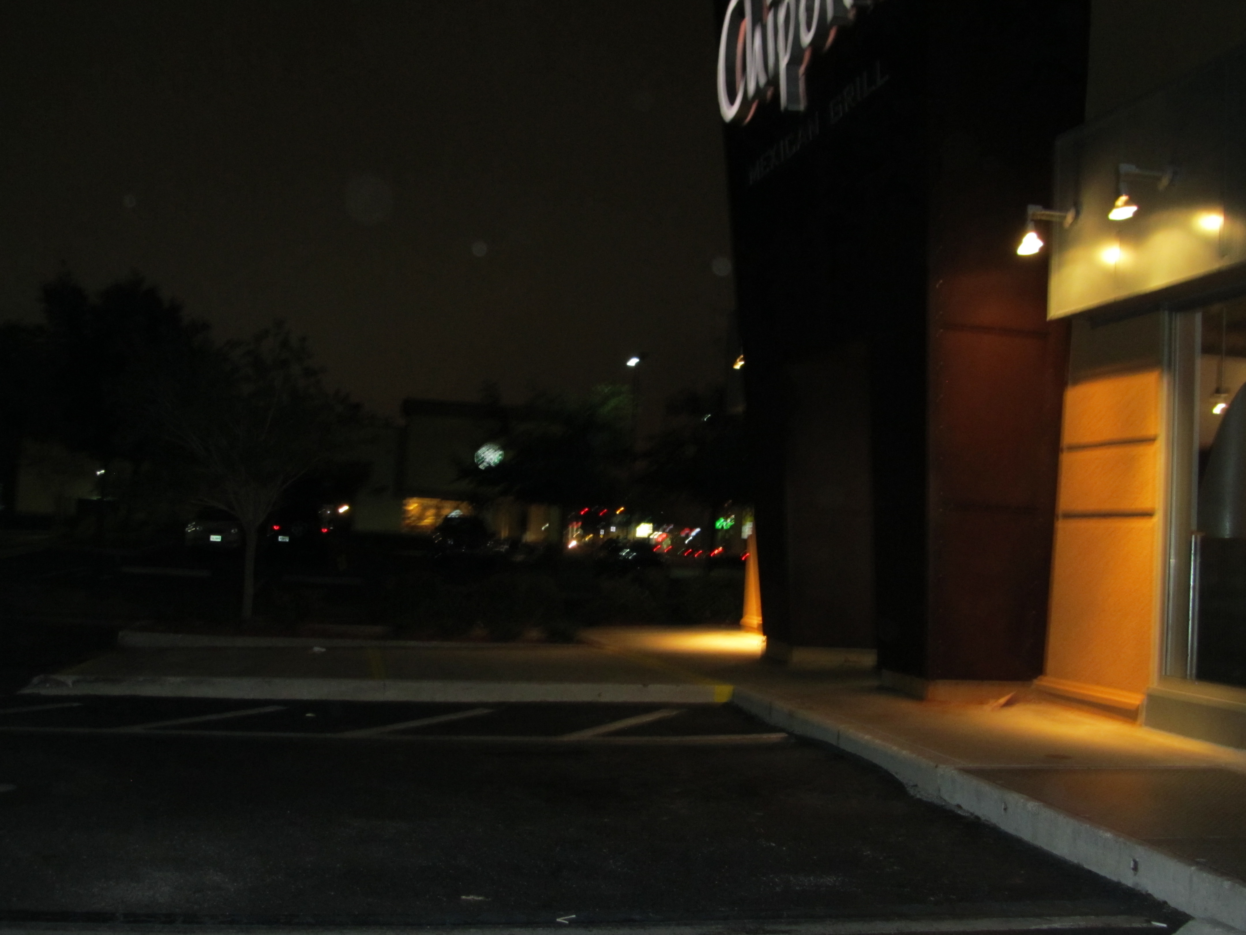 Poorly lit entrance at Chipotle Mexican Grill and unique slant on the curb upon which I tripped due to poor visibility from the parking lot.