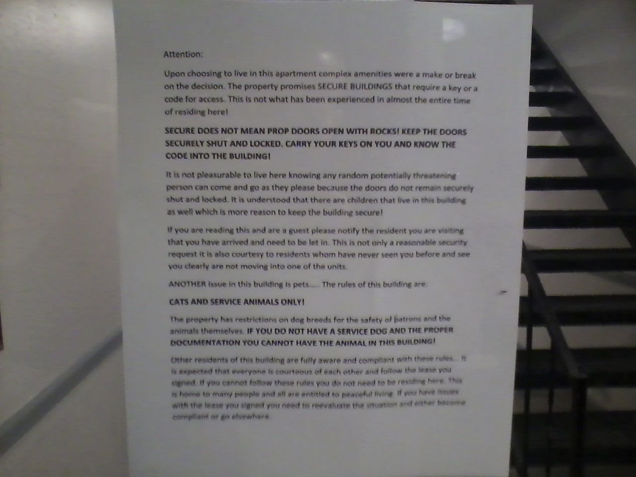 A note on the door of the building complaining about the "security" doors being propped open and people having banned pets.